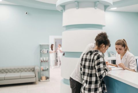 Healthcare professionals assisting at a modern clinic reception desk - Clinic software transition