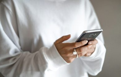 person in white long sleeve shirt holding black smartphone